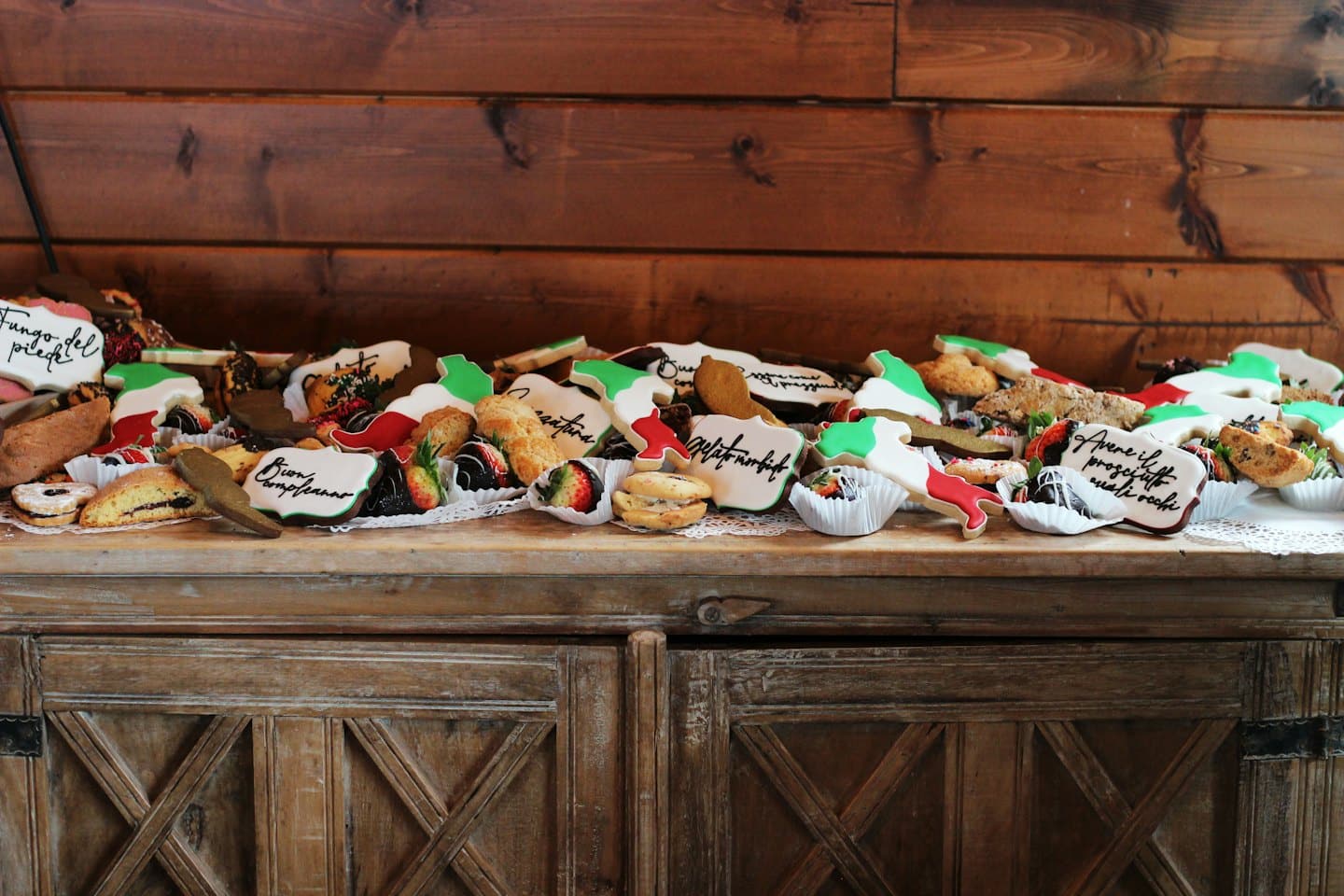 Assortimento di biscotti e pasticcini italiani disposti su un mobile di legno.