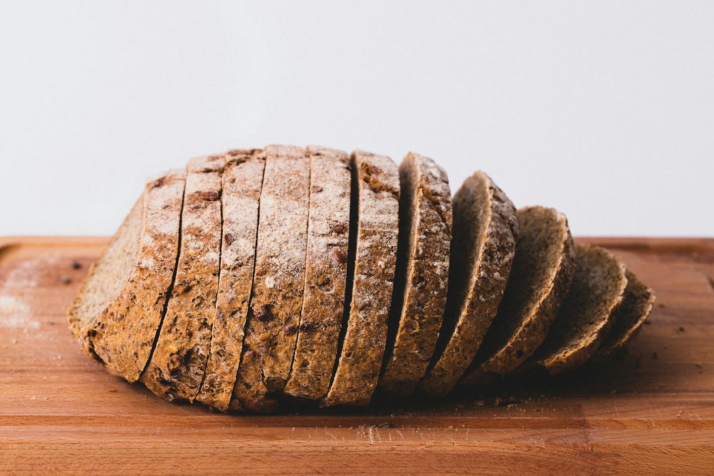 Una pagnotta rustica di pane integrale ai semi su un tagliere di legno.
