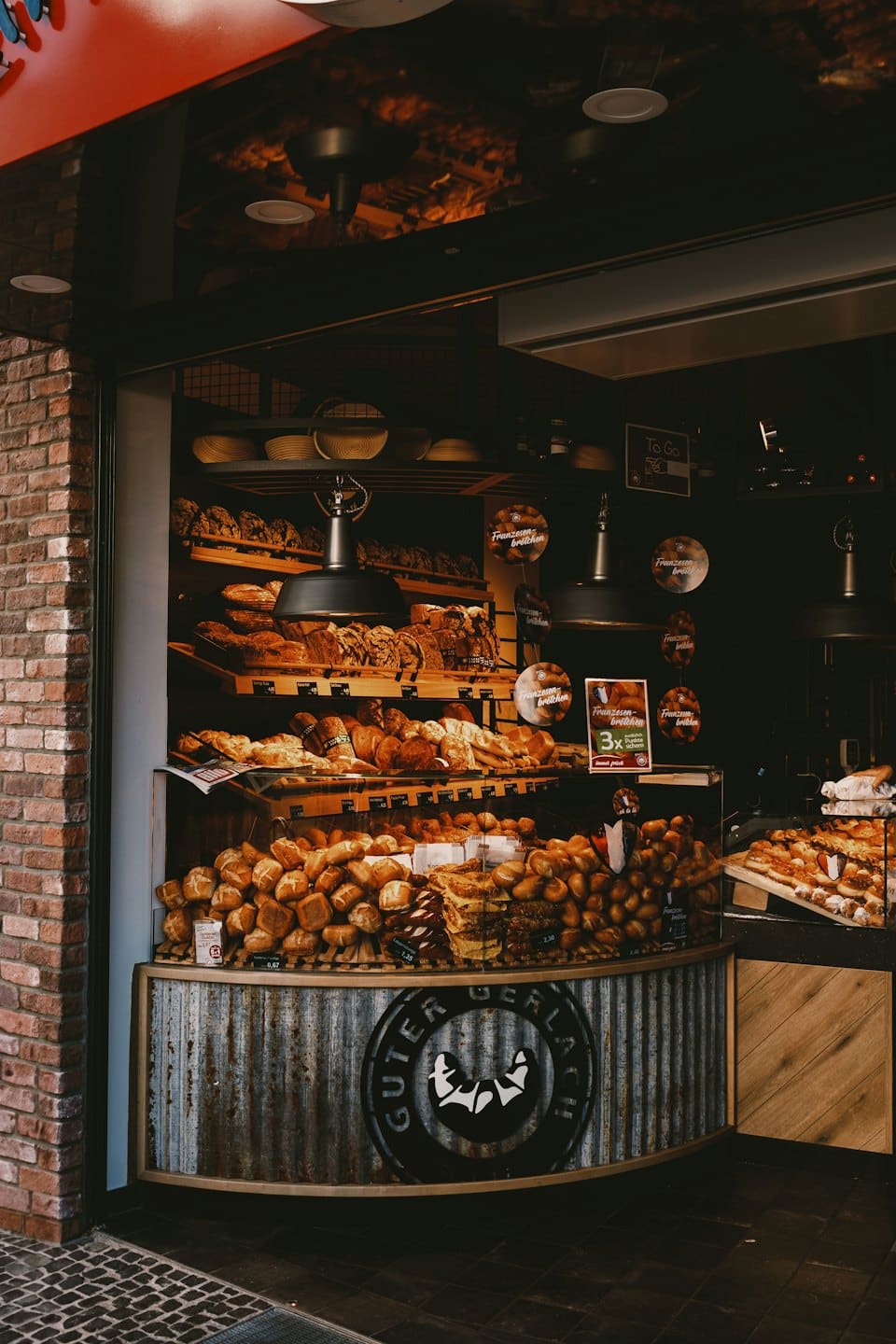 Pane fresco e pasticcini esposti su scaffali rustici di legno.