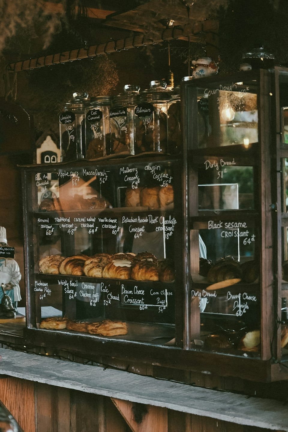 Vetrina di una pasticceria piena di croissant, bignè e danesi.
