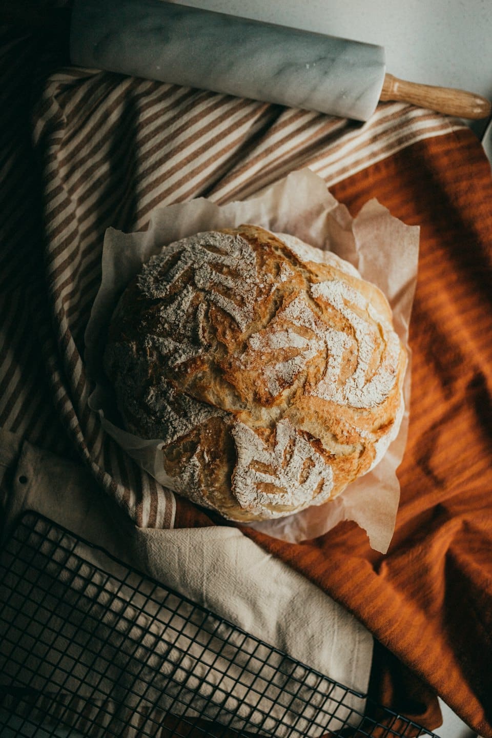 Pagnotta rustica di pane a lievitazione naturale con farina su carta da forno.