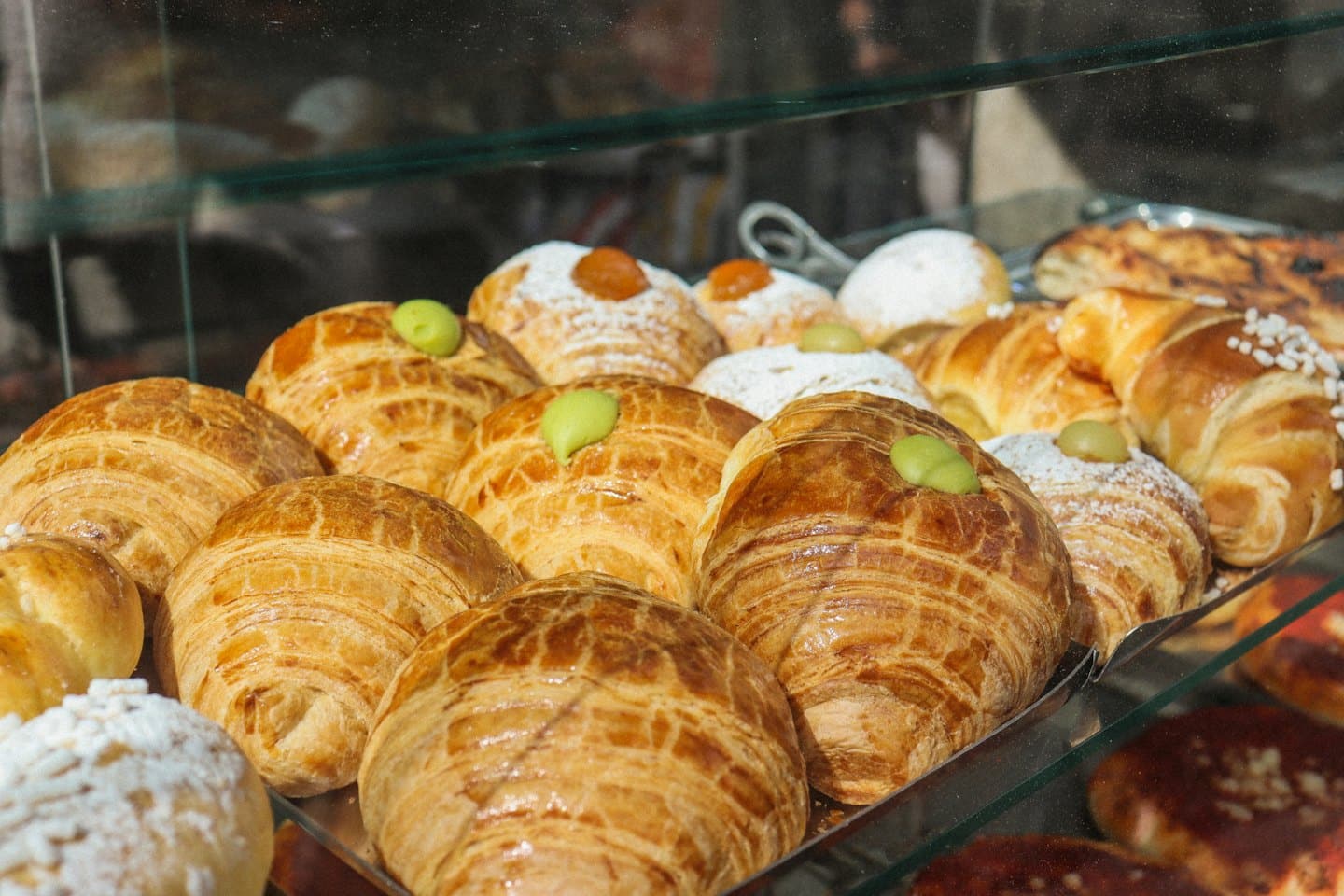 Una varietà di pasticcini freschi esposti all'interno di una vetrina di pasticceria.