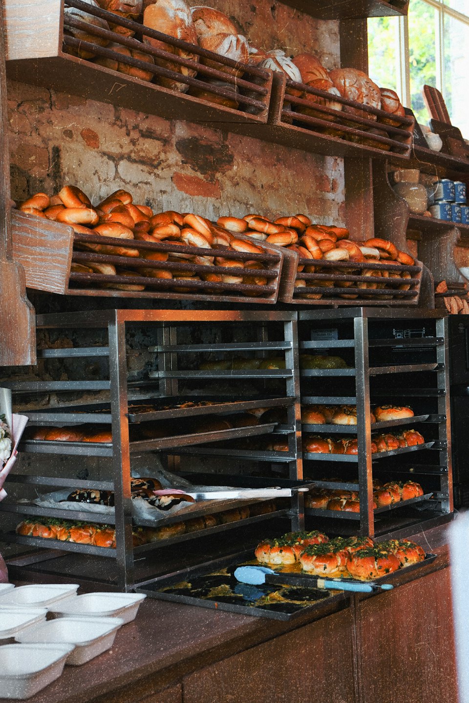 Pane fresco e panini sono disposti sugli scaffali di legno di un panificio.