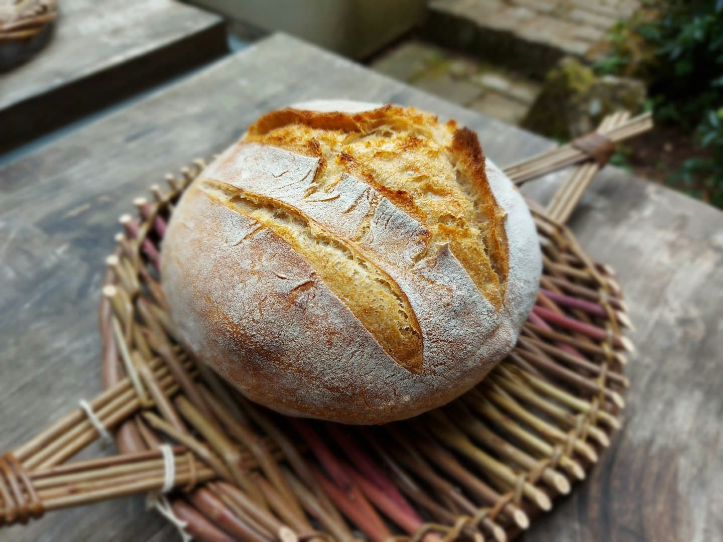 Pane a lievitazione naturale appena sfornato su un vassoio di vimini intrecciato.