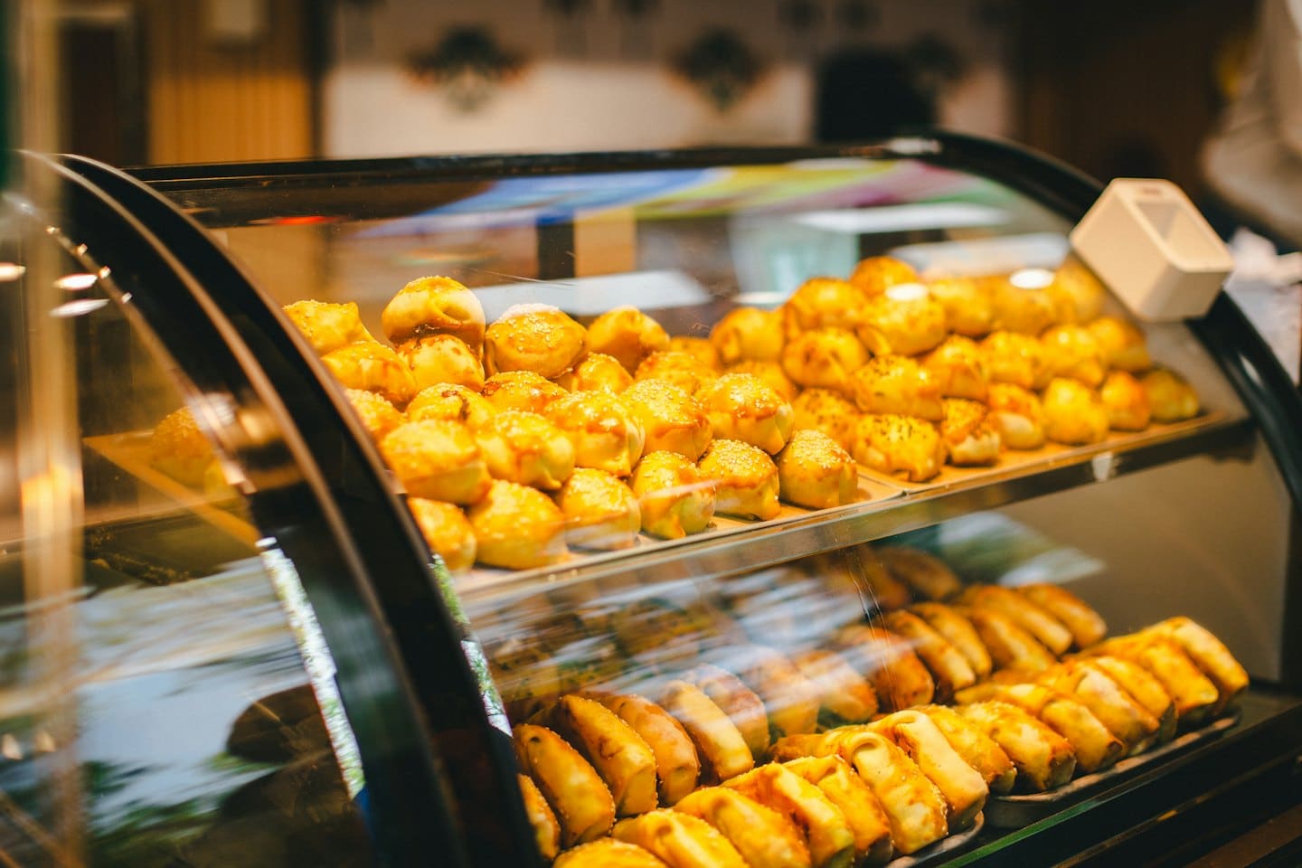 Pasticcini e panini freschi su scaffali in una vetrina.