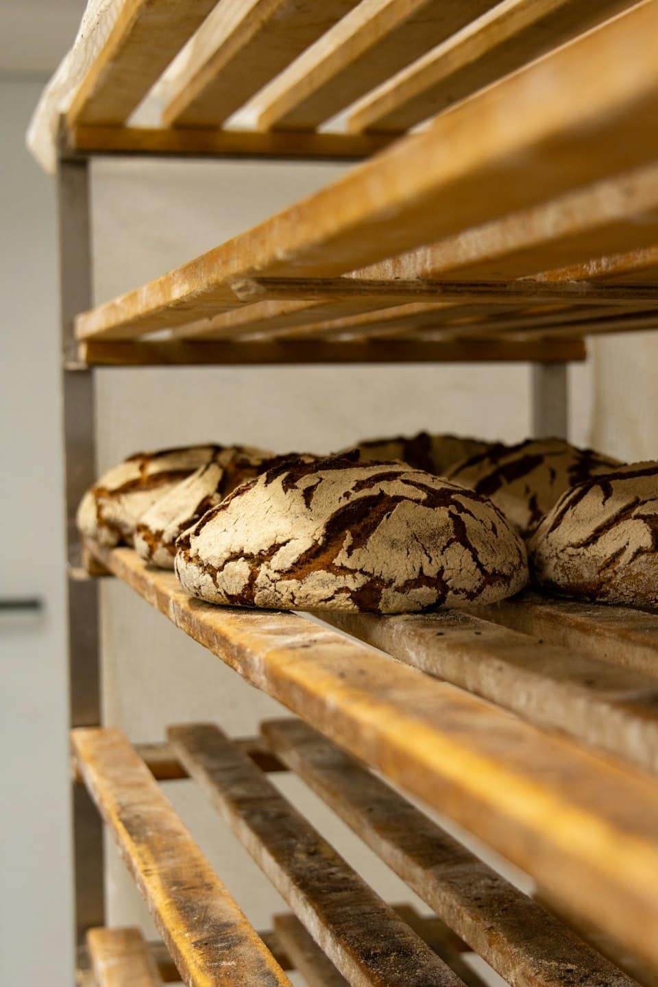 Pane a lievitazione naturale appena sfornato su una rastrelliera di legno.